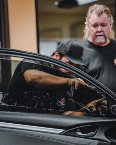 Two men tinting a car window.