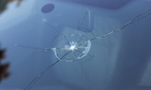 A close-up view of a cracked car windshield in need of windshield repair, displaying a large, star-shaped impact point with radiating cracks.